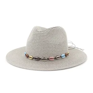 Vue de detail du chapeau de paille de plage d'ete avec bande de perles de coquillage.