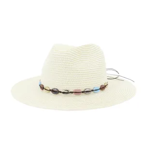 Vue rapprochée d'un chapeau de paille beige orné d'un ruban décoratif de coquillages colorés.