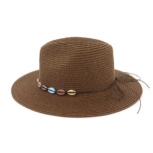 Gros plan du chapeau de paille marron tissé avec des perles de coquillage et cordon en cuir.