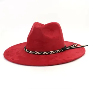 Detail rode suède fedora hoed, brede rand met zwart-witte gevlochten band en stijlvolle kwast.