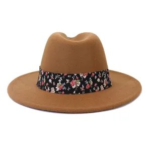 Vista detallada de un sombrero fedora de lana marrón con una elegante cinta floral negra.