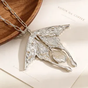 Vue macro du pendentif oiseau en argent texturé sur une chaîne minimaliste élégante et boisée