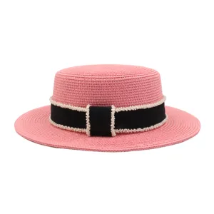 Detailansicht des rosa Strohhats mit schwarzem Band und zarter Perlenbesatzung im Sommer.