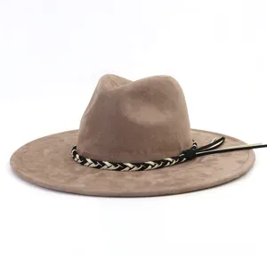 Detailopname van bruine suède fedora hoed met zwart-witte gevlochten band en gladde randtextuur.