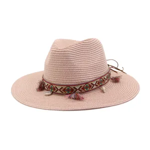 Detailed view of women men straw sun hat beach hat with colorful ethnic band and tassels.