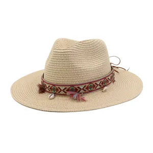 Detail view of woven straw sun hat, featuring ethnic style colorful ribbon, tassels and shells.