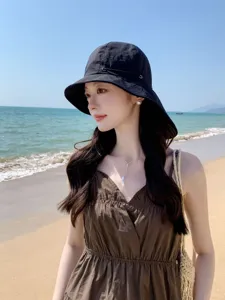Vue détaillée de vacances à la plage d'été avec chapeau de soleil noir et robe élégante.