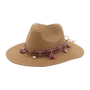 Detailed view of the woven straw sun hat featuring a colorful ethnic ribbon, tassels, and shell accents.