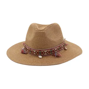 Detailed view of the woven straw beach hat featuring an ethnic ribbon, tassels, and shell accents.