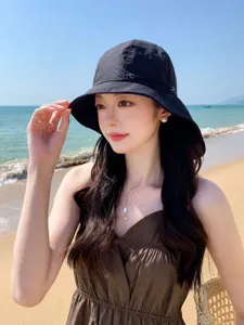 Détail chapeau de soleil plage, large bord anti-UV, bob noir respirant pour voyage d'été.