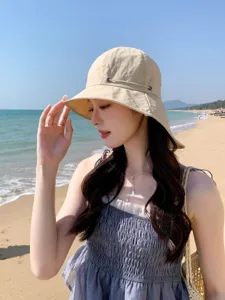 Vue détaillée d'un élégant chapeau de soleil beige porté à la plage en vacances d'été.