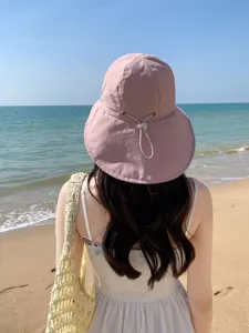 Vue détaillée d'un chapeau de soleil rose avec cordon réglable pour la plage.