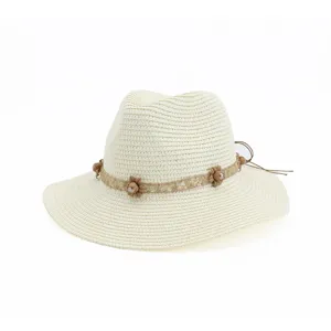 Vue détaillée de l'élégant chapeau de paille blanc avec bande de dentelle et perles.