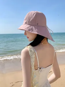 Vue détaillée d'un chapeau de soleil rose à large bord avec cordon de serrage.