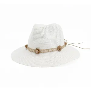 Gros plan détail du chapeau de paille blanc avec bande en dentelle florale et liens.