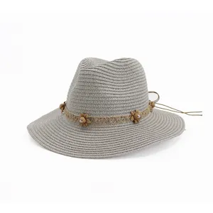 Vue en gros plan de la texture tressée et du ruban floral décoratif sur le chapeau gris.