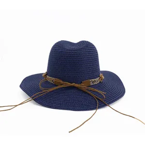 Détail de chapeau de paille bleu marine, avec bande en dentelle et nœud en corde marron.