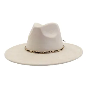 Close-up of off-white suede fedora hat with gold chain band and wide flat brim.