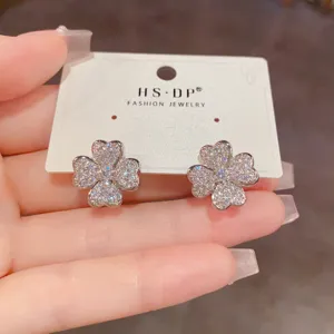 Primer plano detallado de brillantes pendientes de tuerca con trébol de circonita.