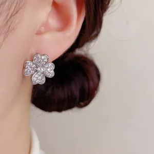 Primer plano detallado de los brillantes pendientes de trébol de circonita en la oreja.