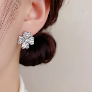 Primer plano detallado de un pendiente de trébol de circonita brillante en la oreja.