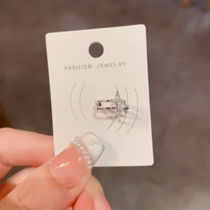 Nahaufnahme des glitzernden Strass-Ohrklemmen-Details auf einer weißen Präsentationskarte.