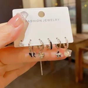 Gedetailleerde opname van trendy zilveren oorbellen set met vlinder en parelhangers.