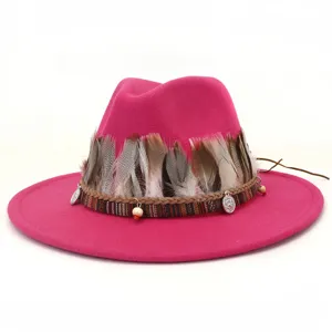 Primer plano detallado del sombrero de lana rosa con decoración de plumas y cuentas étnicas.