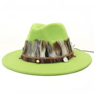 Detalle en primer plano del sombrero fedora de lana verde con plumas étnicas y dijes metálicos.