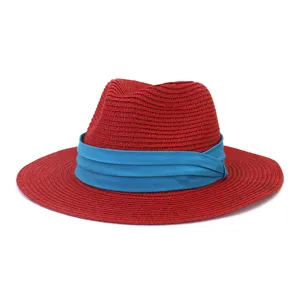 Gros plan du chapeau de paille rouge avec ruban bleu, montrant la texture tressée fine.