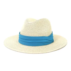 Gros plan détail du chapeau fedora en paille beige avec un élégant ruban en tissu bleu vif.