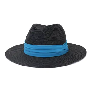 Détail de chapeau fedora en paille noire, avec bande en tissu bleu vif et texture tressée.