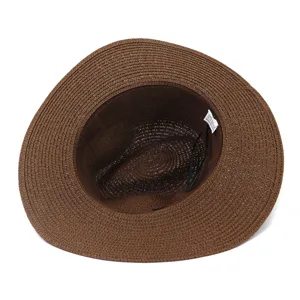 Détail de chapeau de paille tissé marron montrant la texture intérieure et l'étiquette de plage.