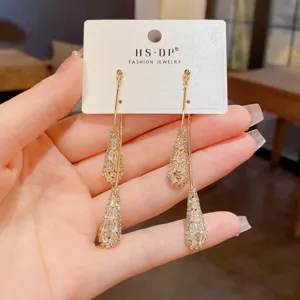 Gros plan de boucles d'oreilles pendantes en zircon étincelant aux détails de cristal exquis.