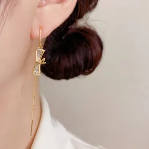 Élégante boucle d'oreille pendante en zircon et bambou doré, style luxueux et brillant.