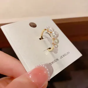 Close-up detail of a minimalist gold open ring featuring gradient pearls and sparkling zircon.