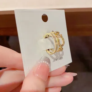 Gold cubic zirconia interlocking ring on display card, exquisite geometric luxury jewelry detail.
