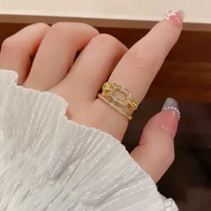Close up detail of a double layer gold ring set with zircon and a unique buckle design.