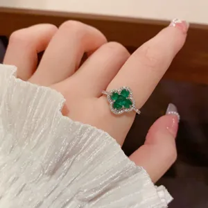 Detail shot of a stylish four-leaf clover green stone zircon open ring, elegant daily wear.
