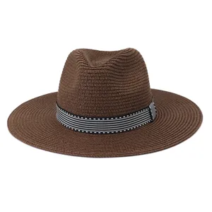 Gros plan sur le chapeau fedora en paille marron, ruban rayé noir et blanc, plage d'été.