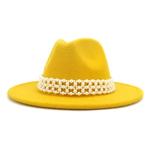Close up detail of yellow wool fedora hat featuring intricate white pearl decorative band.