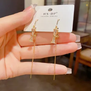 Vue détaillée de longues boucles d'oreilles pompon en bambou zircon, bijoux en or élégants.