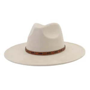 Primer plano detalle del sombrero fedora de ante beige con banda de cuero con tachuelas.