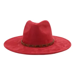 Detalle de sombrero fedora de ante rojo, ala plana ancha, banda de cuero con tachuelas marrones.