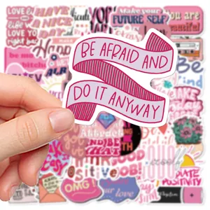 Detail shot of pink inspirational quote sticker featuring empowering text, laptop and journal decor.