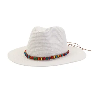 Vue détaillée d'un chapeau de paille blanc avec bande de perles colorées et lanières en cuir.