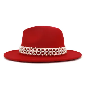 Close-up detail view of elegant red wool fedora hat decorated with gorgeous white pearls.