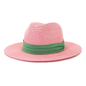 Détail d'un chapeau de paille rose montrant la texture tressée fine et le ruban vert.