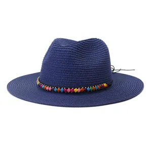 Gros plan sur le chapeau fedora en paille bleue avec une bande de perles en bois.