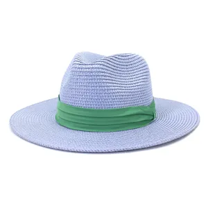 Gros plan détaillé de la texture en paille tressée et du ruban vert sur le chapeau fedora.